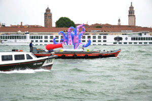 vaporetto e imbarcazione con scultura di una piovra a Venezia